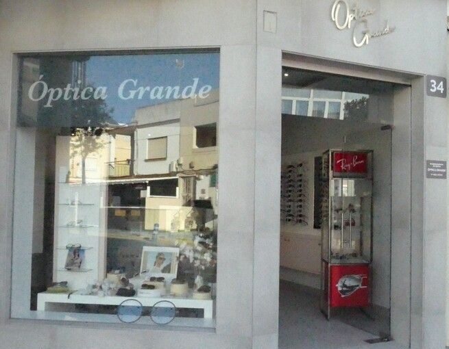 Fachada de Óptica Grande: escaparate con monturas y la puerta abierta al interior de la tienda